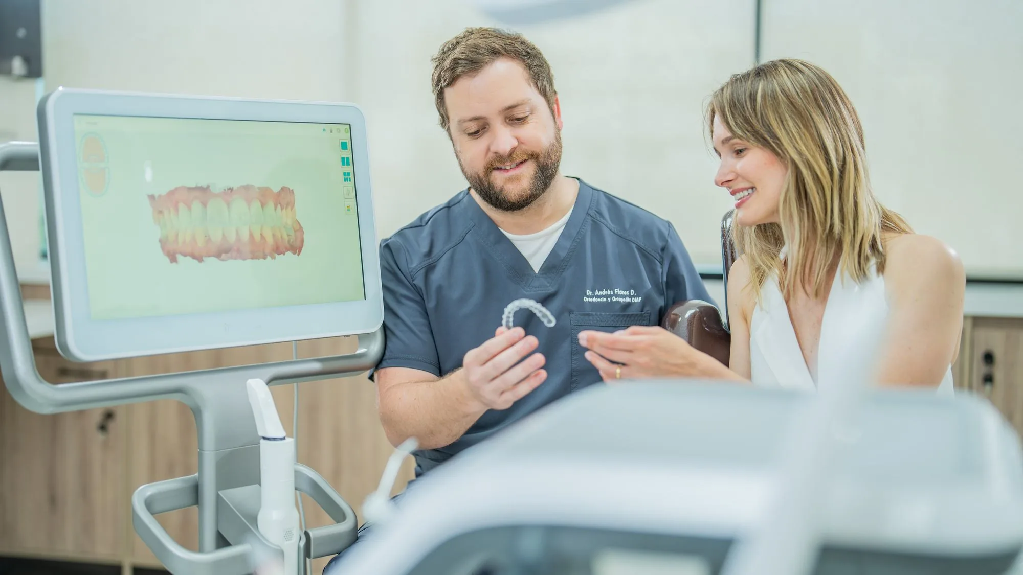 Dr. Andrés Flores mostrando un alineador Invisalign a una paciente en Zenclinic